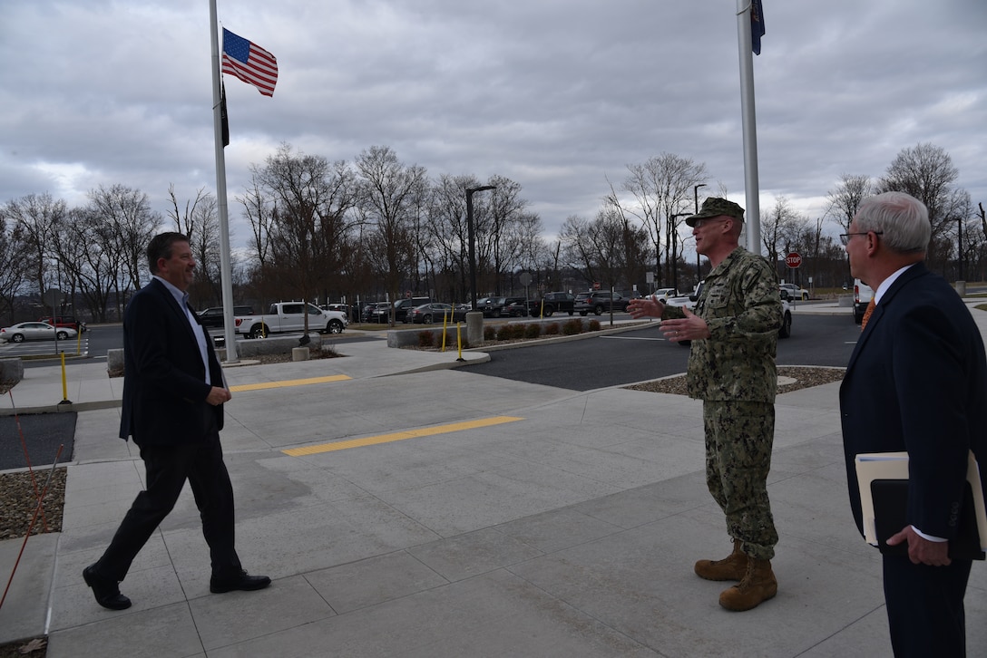 Brad Bunn meets Rear Adm. Grafton D. Chase, Jra nd Perry L. Knight outside of DLA Distribution with flags in the background