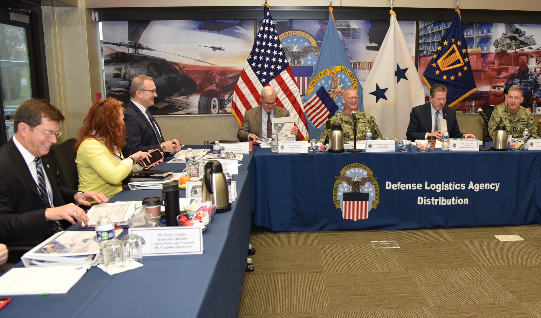 DLA leaders are assembled behind center-facing tables in a conference room