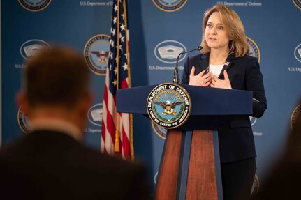 A woman gestures with her hands while she speaks before a crowd of people.