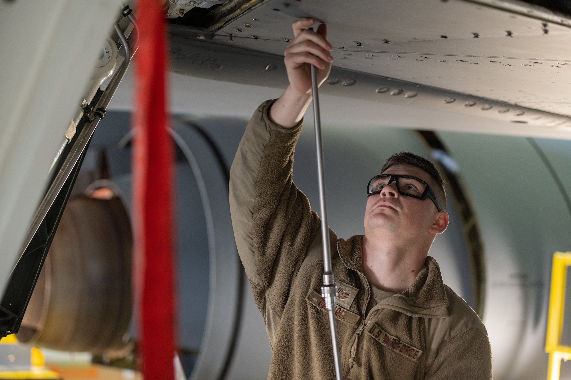 An aircraft maintainer works on the underside of a KC-135 wing.