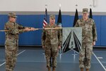 Three men in uniform unveiling guidon