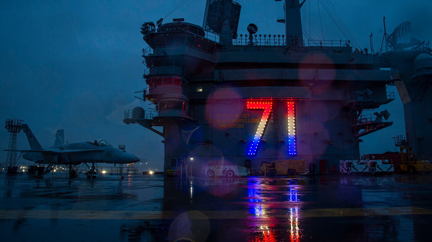 The hull number of the Nimitz-class aircraft carrier USS Theodore Roosevelt (CVN 71) is illuminated at sundown March 12, 2023.