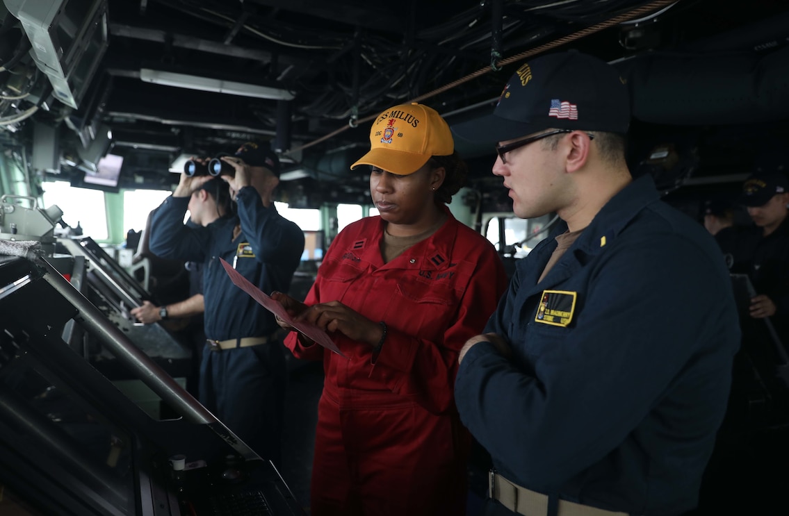 Lt. Kayla Reddish, left, from Jacksonville, Florida, and Ensign Zachary Bradberry, from Pflugerville, Texas, review navigation procedures on the bridge aboard the Arleigh Burke-class guided-missile destroyer USS Milius (DDG 69) while operating in the Philippine Sea.