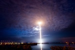 A rocket launches into dark blue, cloudy sky.