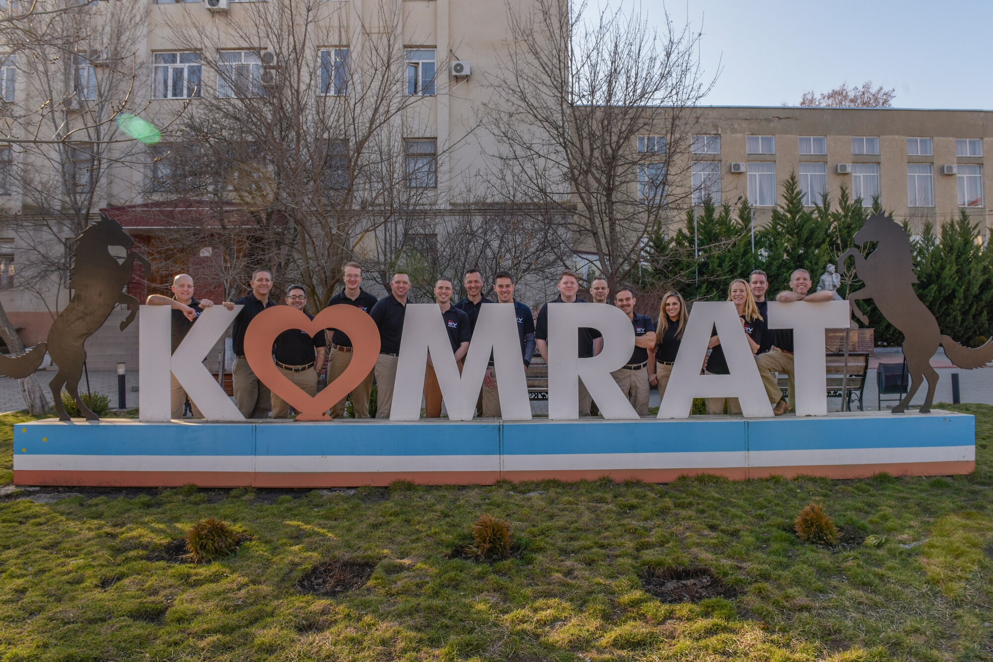 People stand behind a sign that says "Komrat"