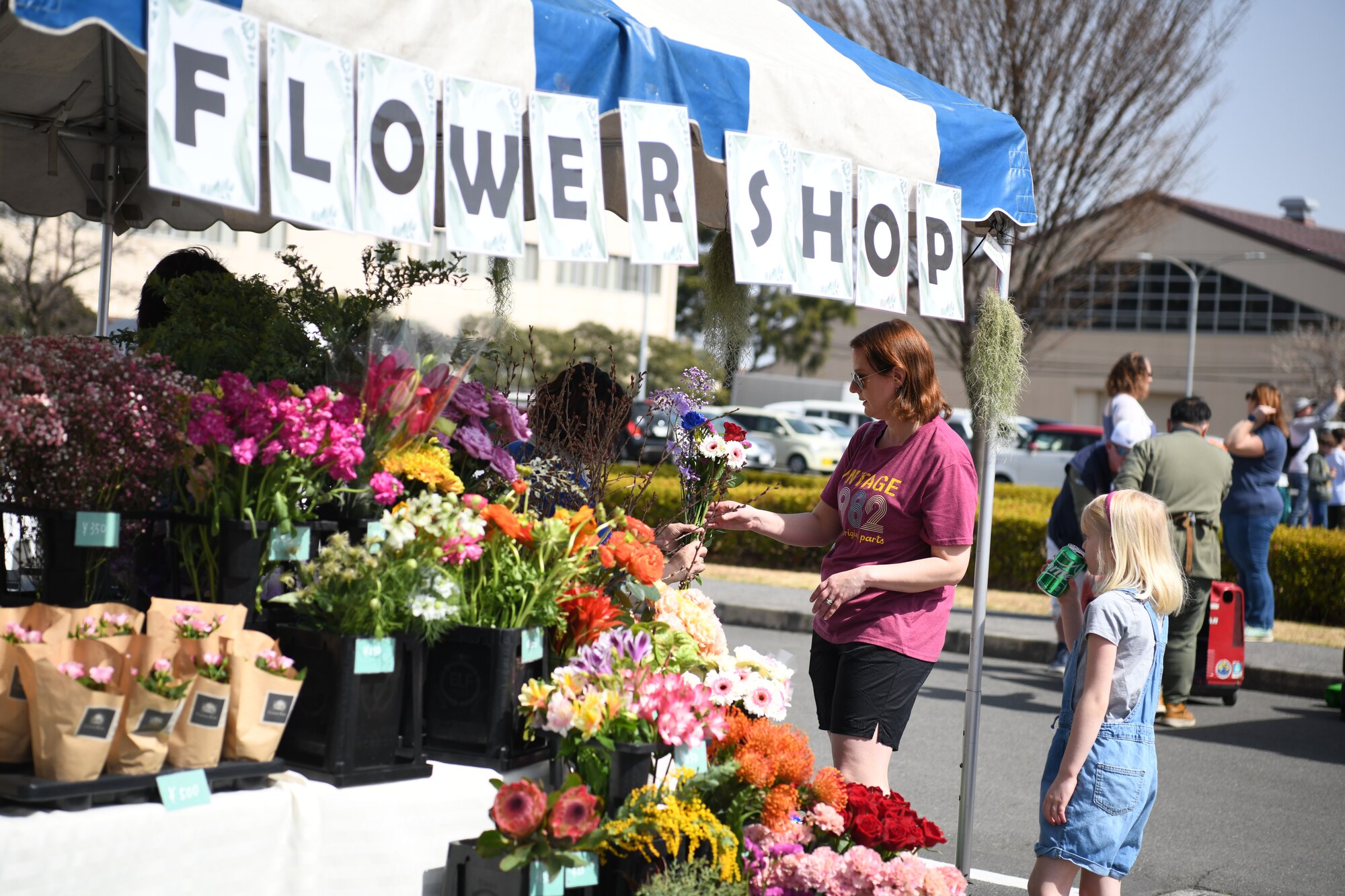 A woman wearing a pink shirt looks at flowers.