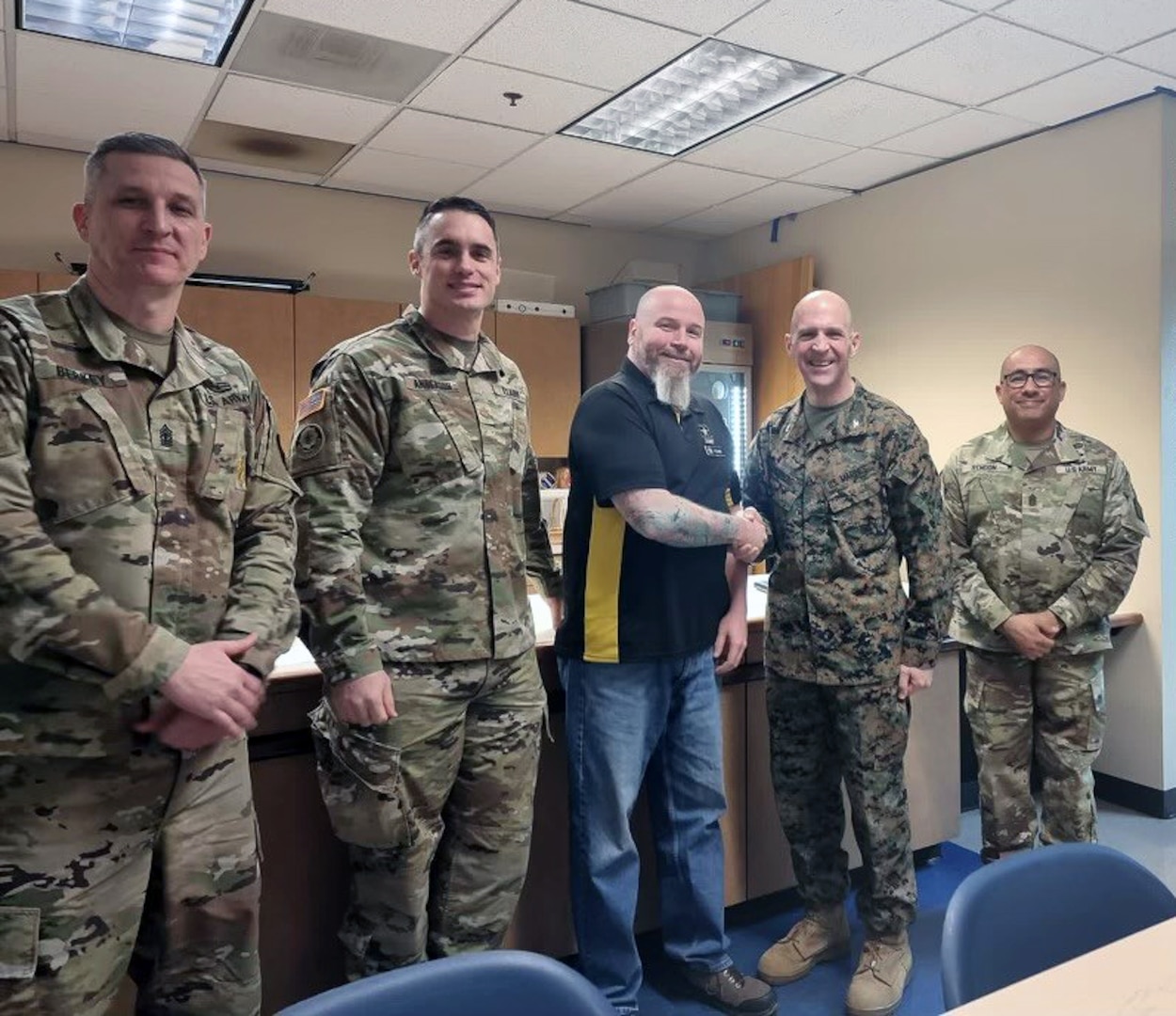 Dave Foland, administrative support technician, Portland MEPS, (center) is presented with the Western Sector Coin for Excellence by Marine Corps Col. Jesse Sjoberg, USMEPCOM Western Sector commander. Foland was recognized for intervening and disarming a possible active shooter in Troutdale, Ore.