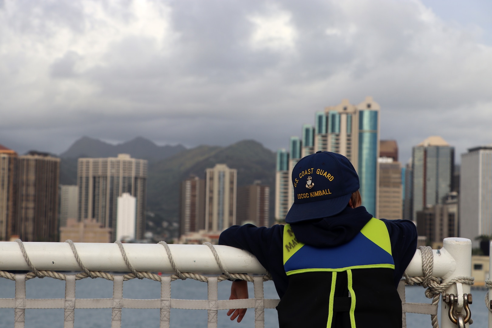 The famliy member of a U.S. Coast Guard Cutter Kimball (WMSL 756) crew member looks at Honolulu's skyline from the Kimball as Kimball returns to Honolulu following a 42-day Western Pacific patrol, March 10, 2023. Kimball was the first U.S. military ship in recent history to visit the port city of Kagoshima, Japan, during their patrol where the crew partnered with servicemembers from Japan Coast Guard’s 10th District to plan and conduct combined operations and search-and-rescue exercises. U.S. Coast Guard photo by Ens. Philip Rogers.