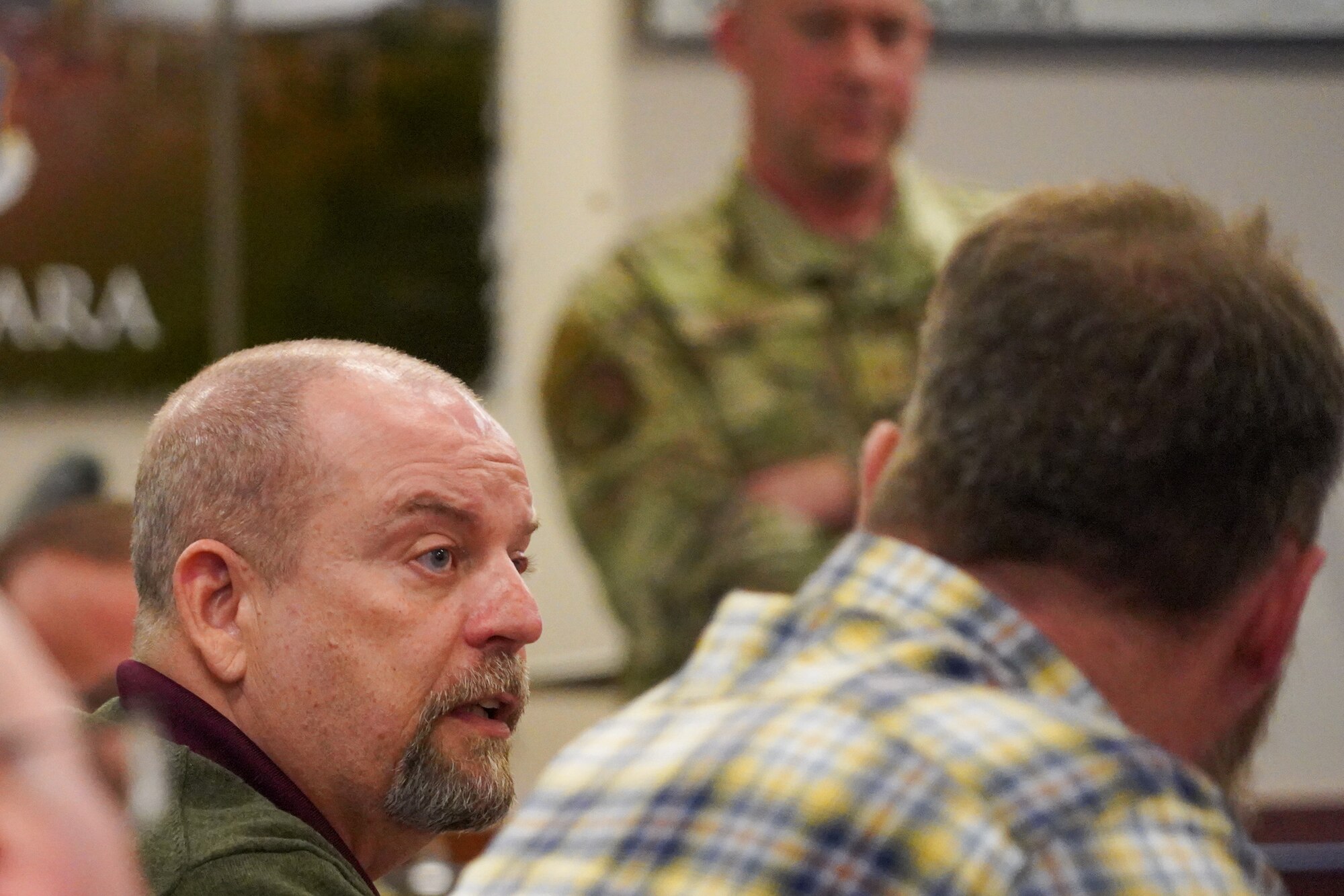 Man speaking to briefing room filled with other people.