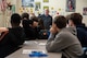 Man standing at the front of a classroom, giving a presentation.