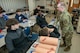 Male Army Soldier demonstrates how to stop bleeding to a school of high school students.