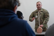 Male Soldier demonstrates first aid to high school students.