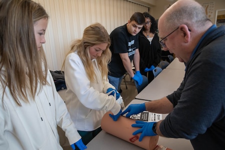 man using a medical dummy arm to demonstrate medical procedures.