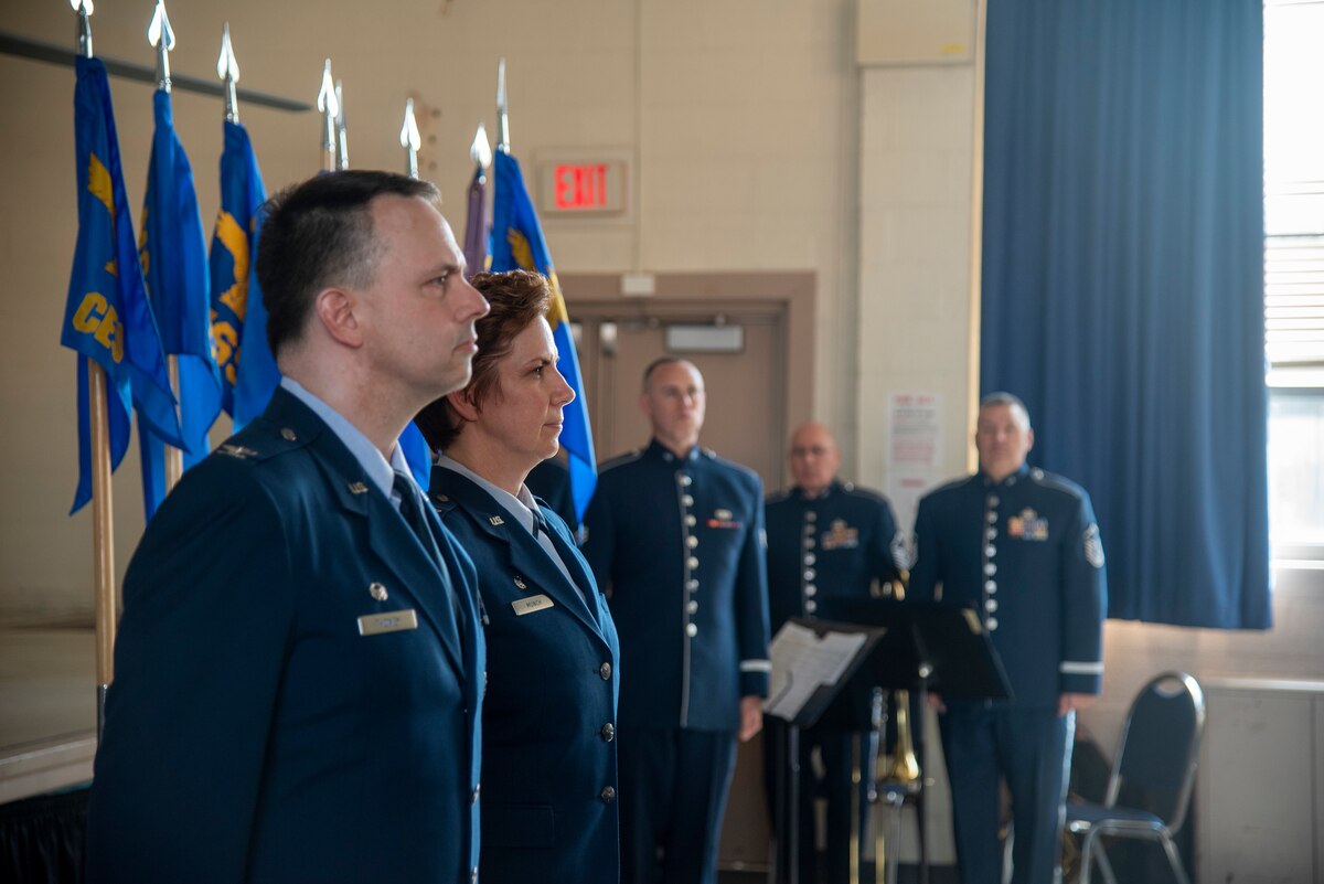 A man and woman in Air Force Dress blues stand at attention.