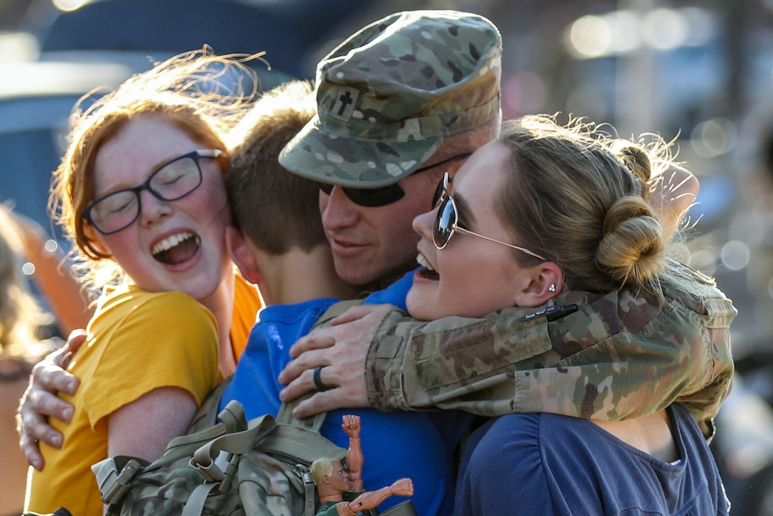 A soldier hugs three family members.