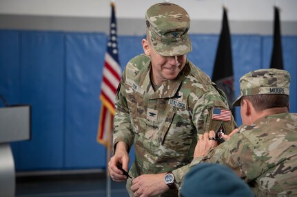 Man putting patch on the sleeve of another man in military uniform