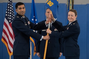 Two people in military uniform holding a flag.