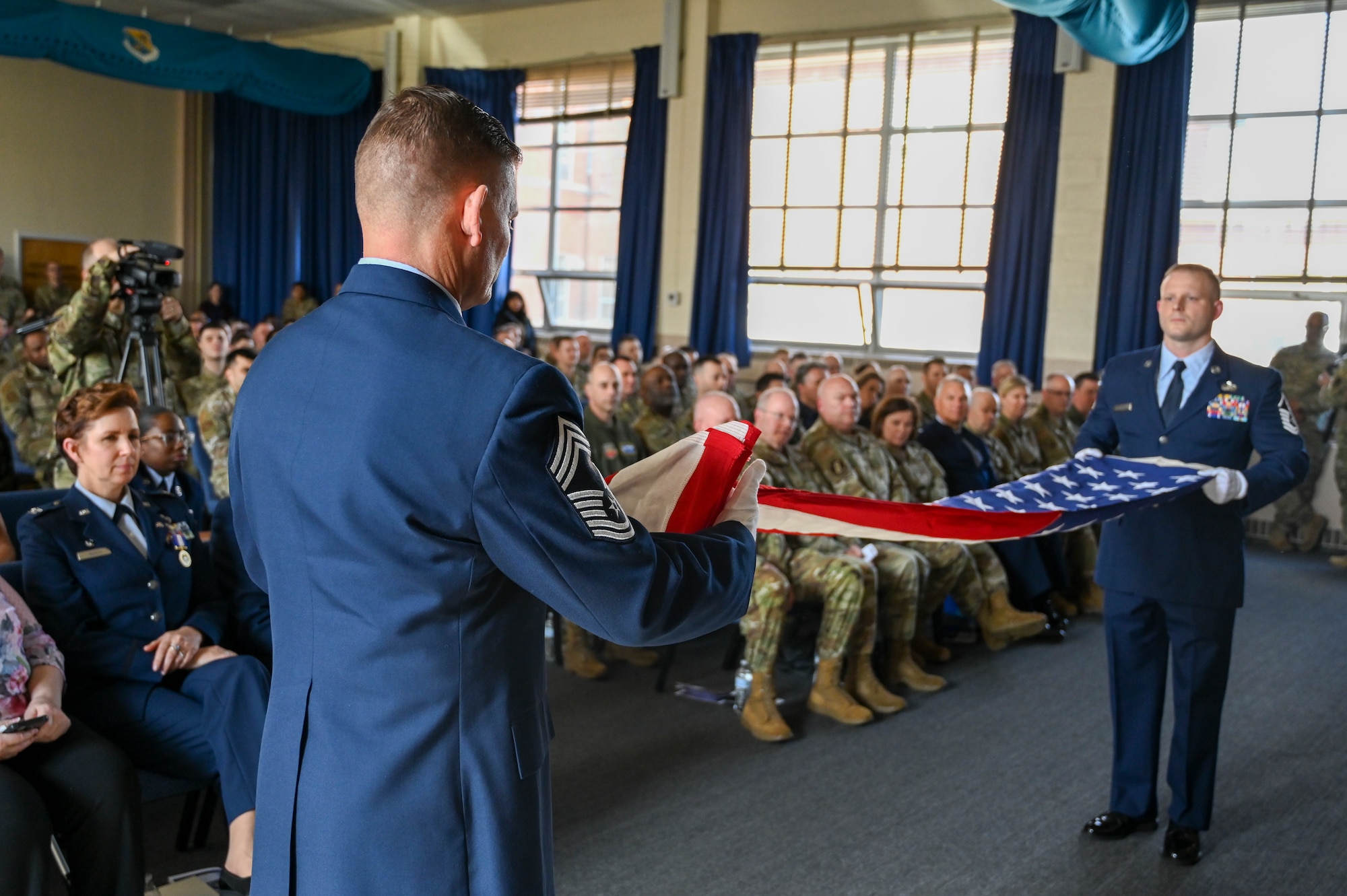 Two men in uniform fold a flag.