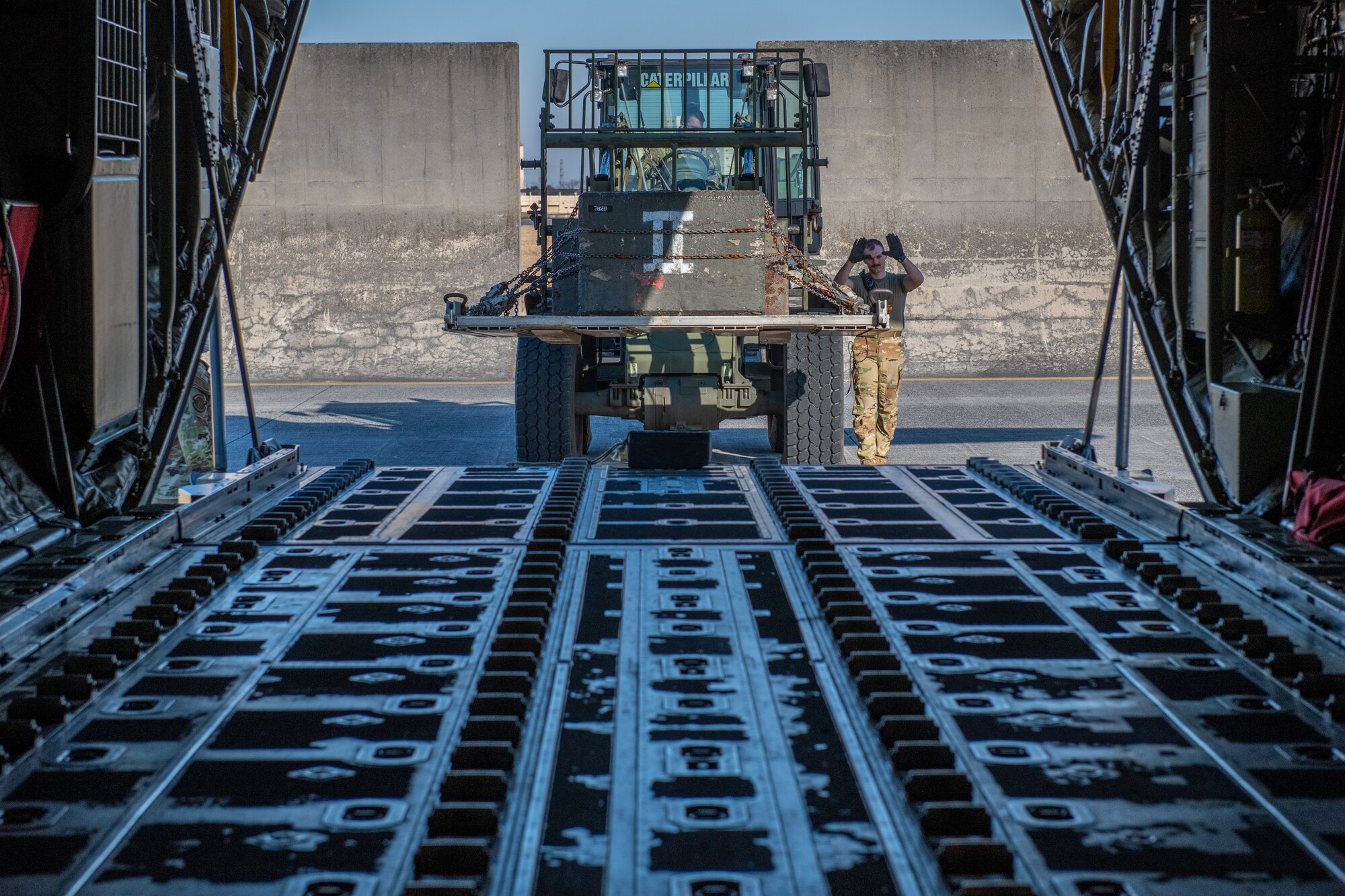 Airmen guide cargo onto the ramp of a C-130J
