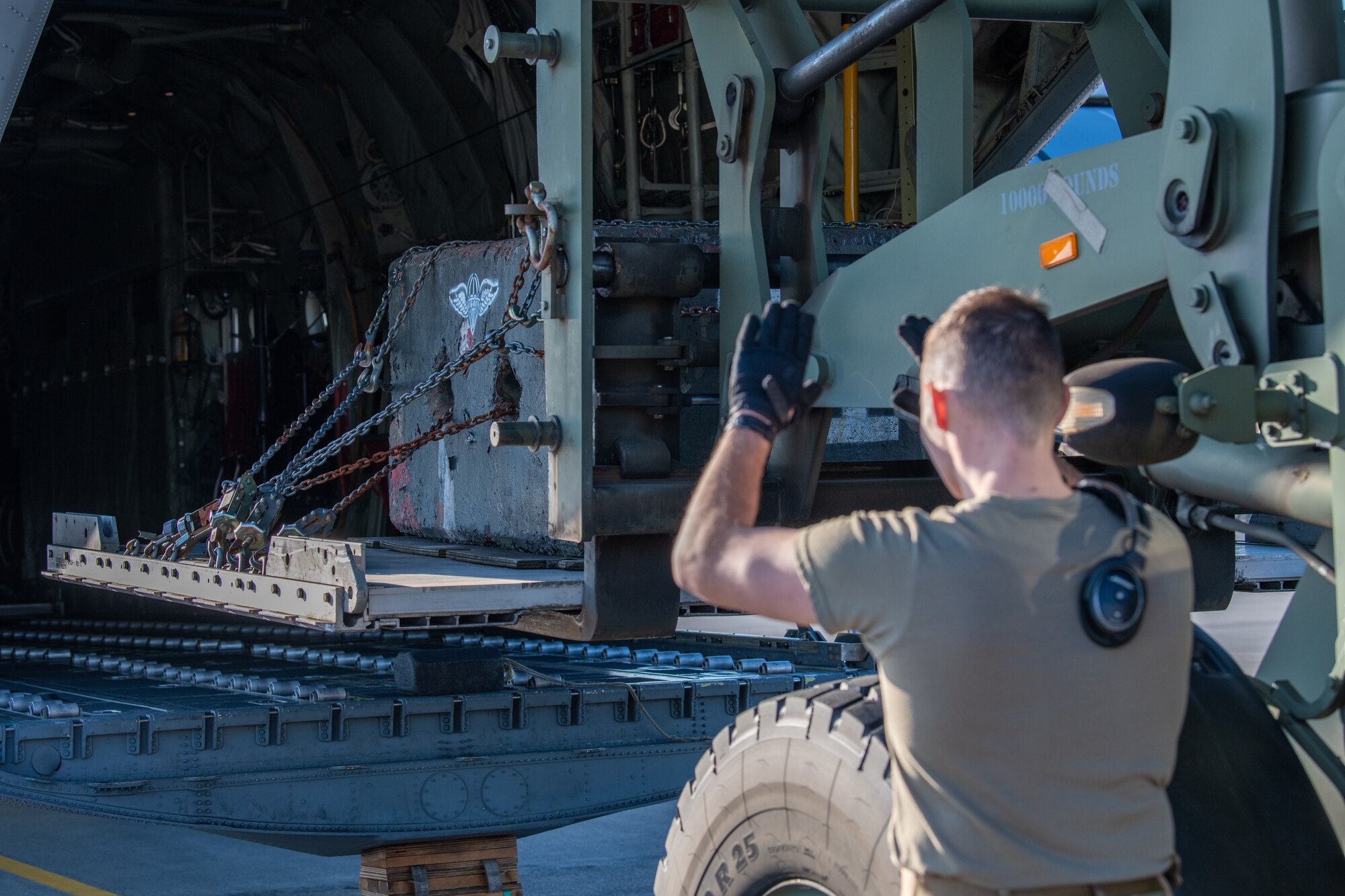 Airman guides cargo onto the ramp of a C-130J