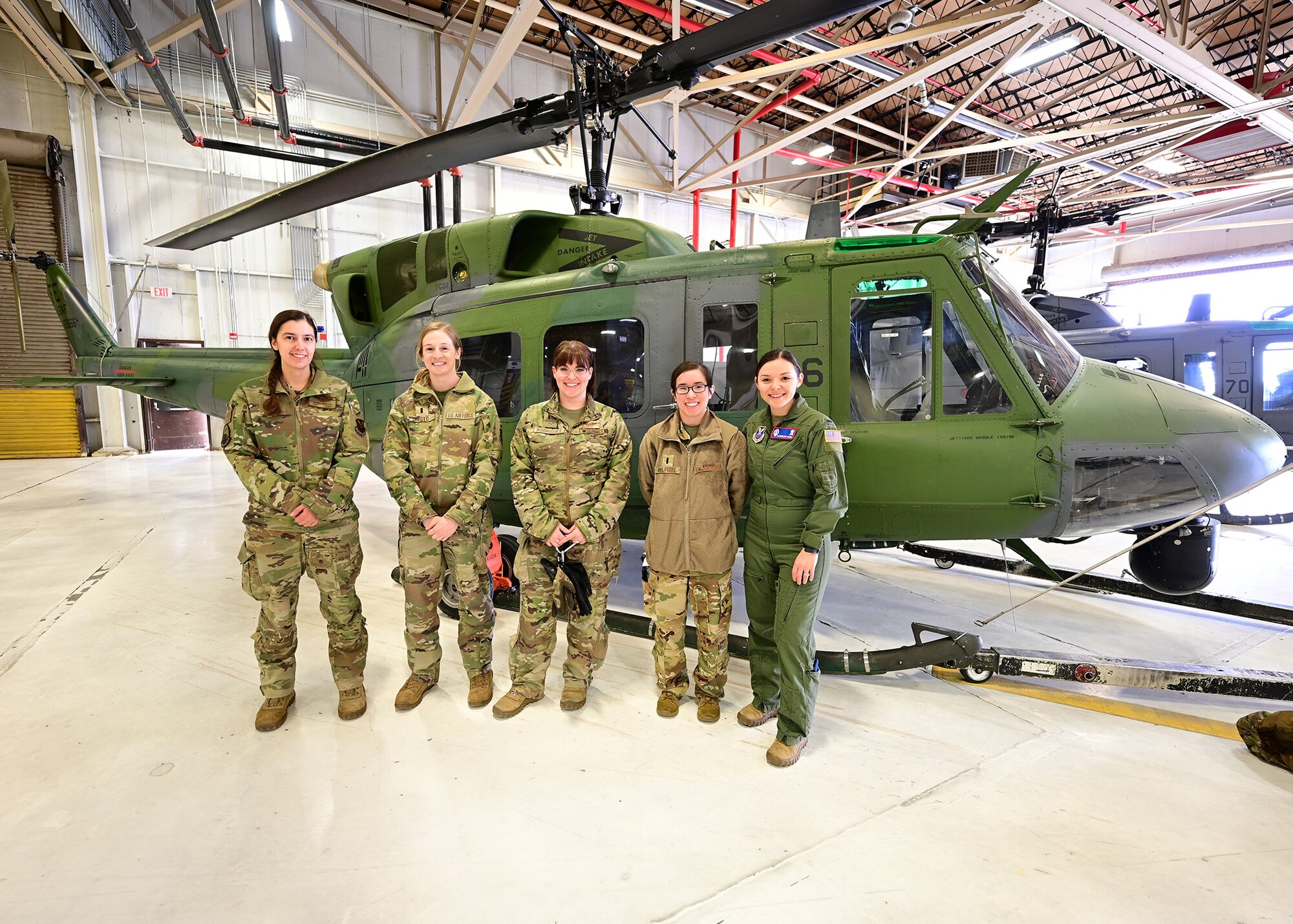 female airmen pose for a photo in front of an U1-N1 Huey