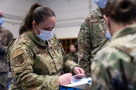 U.S. Air Force Maj. Christen Chandler writes down notes on a paper in front of an Airman