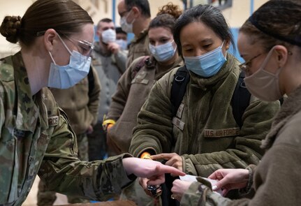 U.S. Senior Airman Juyeon Park stands at the head of a line of patients being checked in at a table
