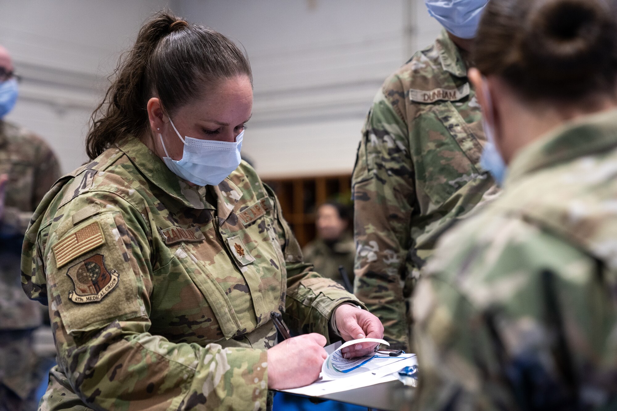 U.S. Air Force Maj. Christen Chandler writes down notes on a paper in front of an Airman