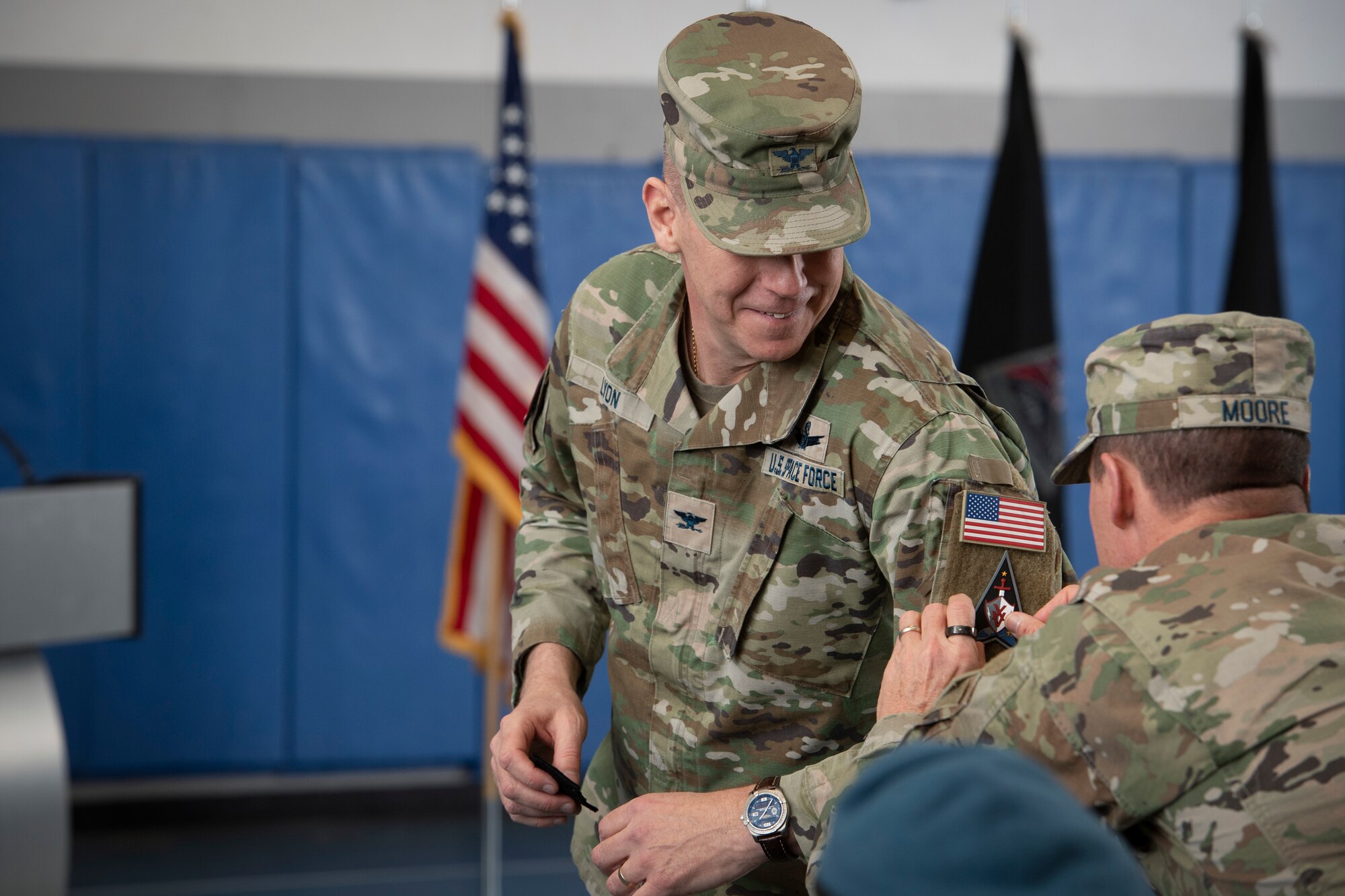 Man putting patch on the sleeve of another man in military uniform