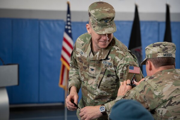 Man putting patch on the sleeve of another man in military uniform