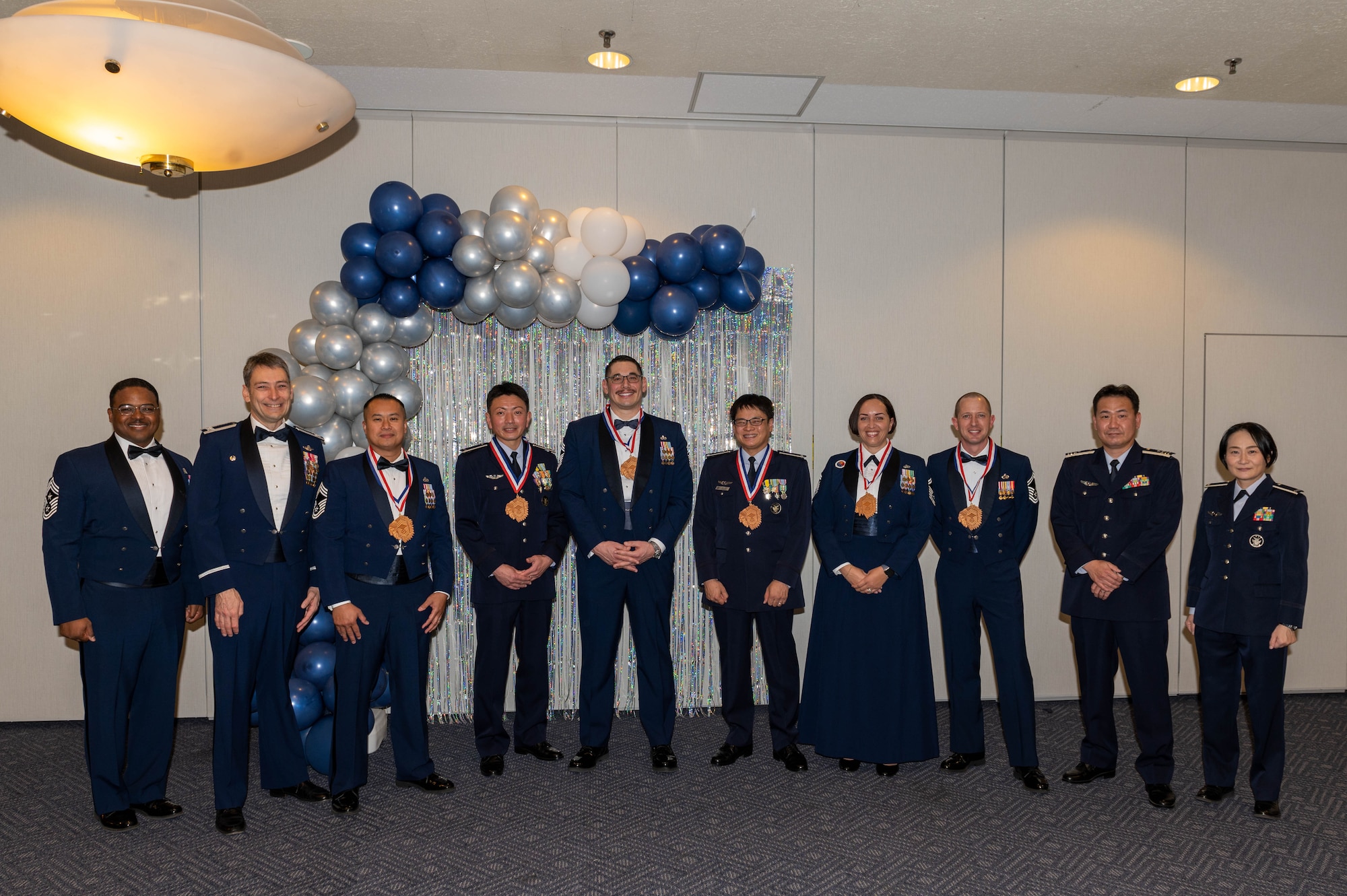 Ten people dressed in formal attire pose for a photo.