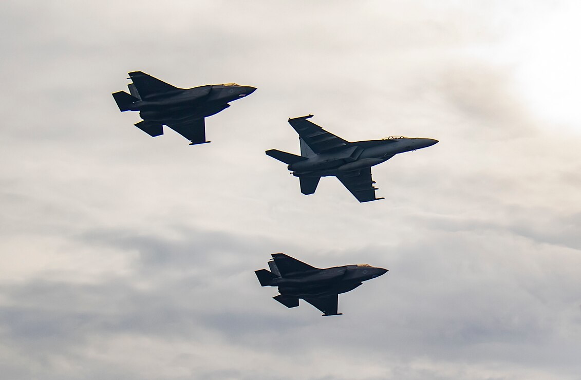 Aircraft from Nimitz Carrier Strike Group (NIMCSG) and Makin Island Amphibious Ready Group (MKI ARG) fly in formation past the aircraft carrier USS Nimitz (CVN 68). NIMCSG and MKI ARG, with embarked 13th Marine Expeditionary Unit (13th MEU), are conducting combined expeditionary strike force (ESF) operations in the South China Sea as part of continuing and routine interoperability training in the Indo-Pacific region.