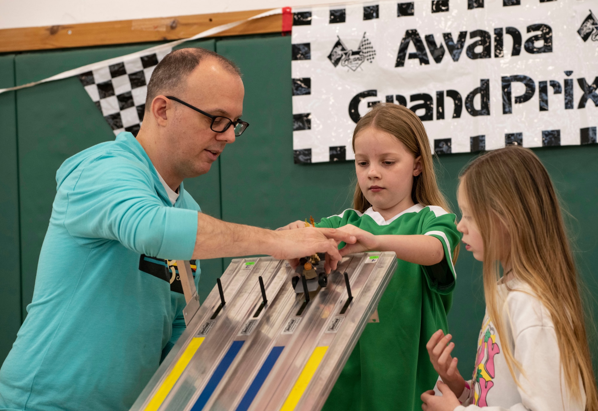 Capt. Steven Davis, 501st Combat Support Wing chaplain, helps a child set up their pinewood derby car for a test run at RAF Alconbury