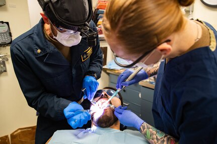 Lt. Cmdr. Nicholas Bennetts, from Helena, Montana, an oral surgeon assigned to the first-in-class aircraft carrier USS Gerald R. Ford (CVN 78), and Hospital Corpsman 2nd Class Abigail Riddle, from Woodruff, South Carolina, extract a tooth from Machinist's Mate (Nuclear) 2nd Class Armann Huerta, from Detroit, March 14, 2023. Ford is underway in the Atlantic Ocean executing its Composite Training Unit Exercise (COMPTUEX), an intense, multi-week exercise designed to fully integrate a carrier strike group as a cohesive, multi-mission fighting force and to test their ability to carry out sustained combat operations from the sea. As the first-in-class ship of Ford-class aircraft carriers, CVN 78 represents a generational leap in the U.S. Navy's capacity to project power on a global scale. (U.S. Navy photo by Mass Communication Specialist 2nd Class Jennifer A. Newsome)