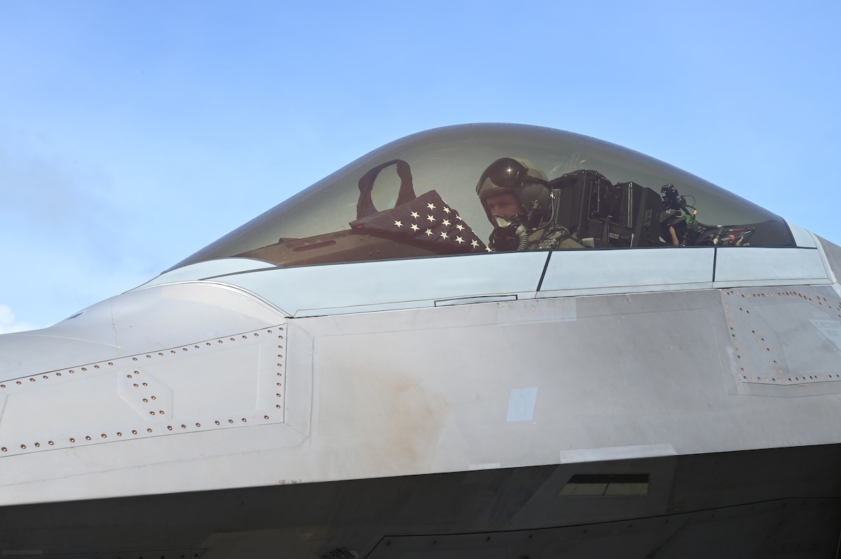 Romo, an F-22 Raptor pilot assigned to the 525th Expeditionary Fighter Squadron, prepares to fly a training sortie while displaying an American flag during Exercise Agile Reaper 23-1 at Tinian International Airport, Northern Mariana Islands, March 3, 2023. While at Tinian, a deceased prior Army service member was returned to her birthplace, and the 3rd AEW paid their respects to her and her family by flying the flag in an F-22 Raptor and providing it to the family upon the member’s arrival. (U.S. Air Force photo by Tech. Sgt. Hailey Staker)