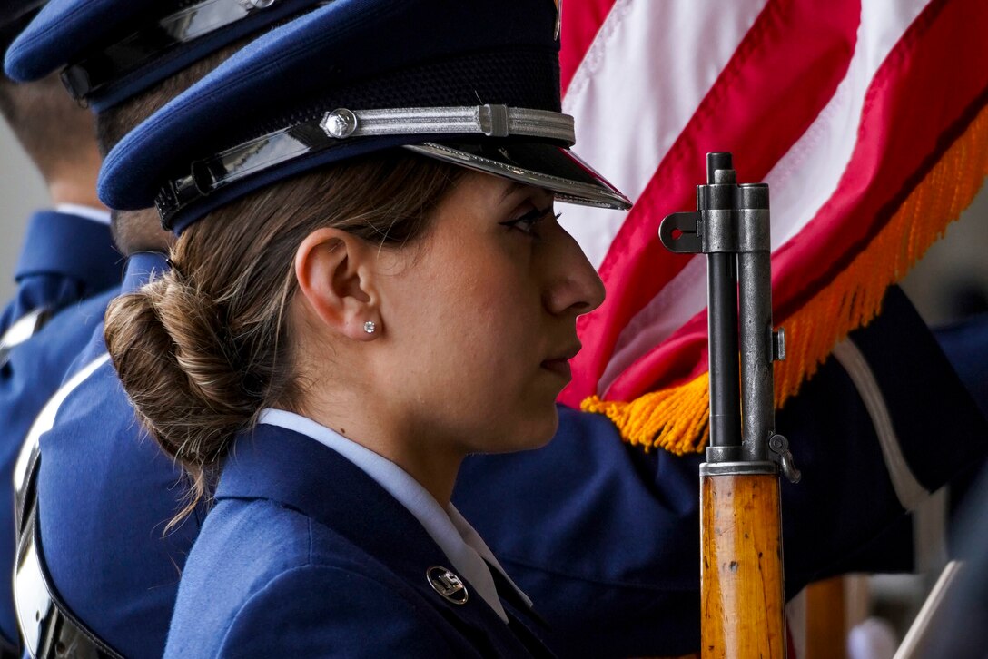 An airman in a formal uniform stands at attention during a ceremony.