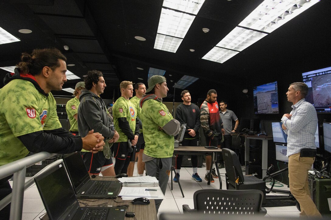 Rugby players from the San Diego Legion Rugby Team are briefed the basics of a Marine Corps battle simulator at Marine Corps Air Ground Combat Center (MCAGCC), Twentynine Palms, California, Jan. 19, 2023. The team visited MCAGCC to improve unit cohesion, morale, and train in a different environment to improve their performance. (U.S. Marine Corps photo by Lance Cpl. Anna Higman)