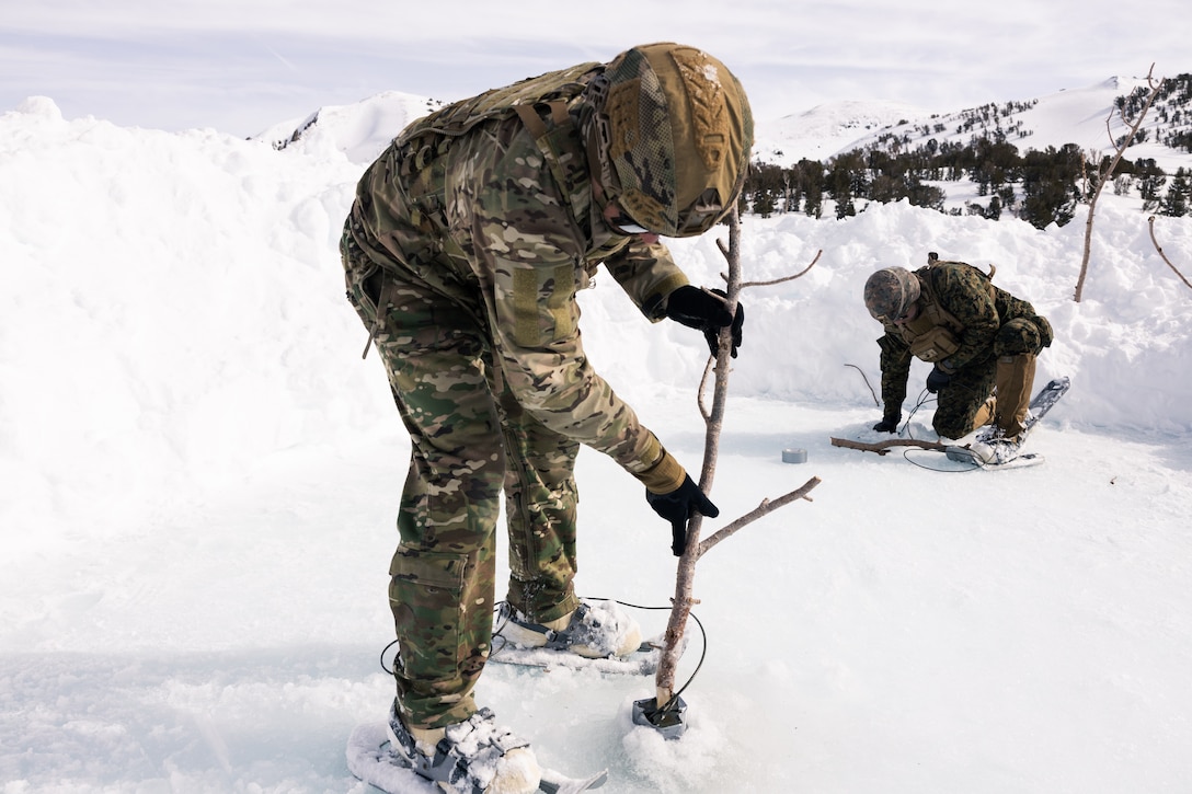 Two US Marines place explosives into the ice of a frozen lake