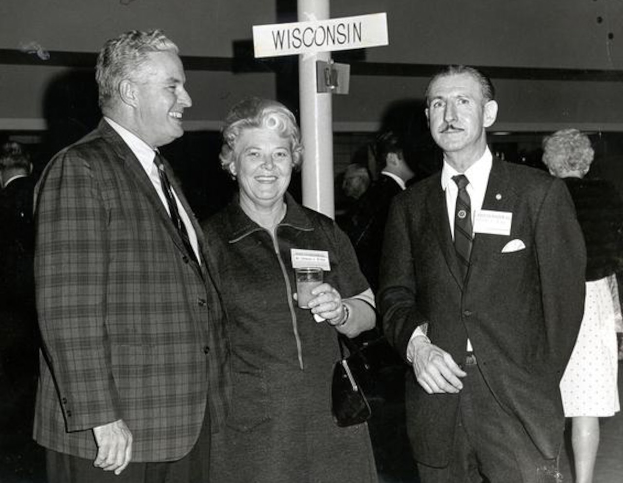 Two men and a woman stand near each other.