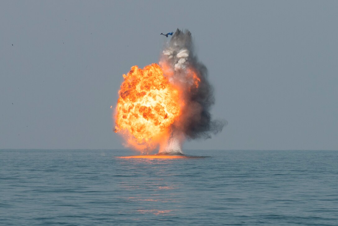 A floating device explodes over a body of water.