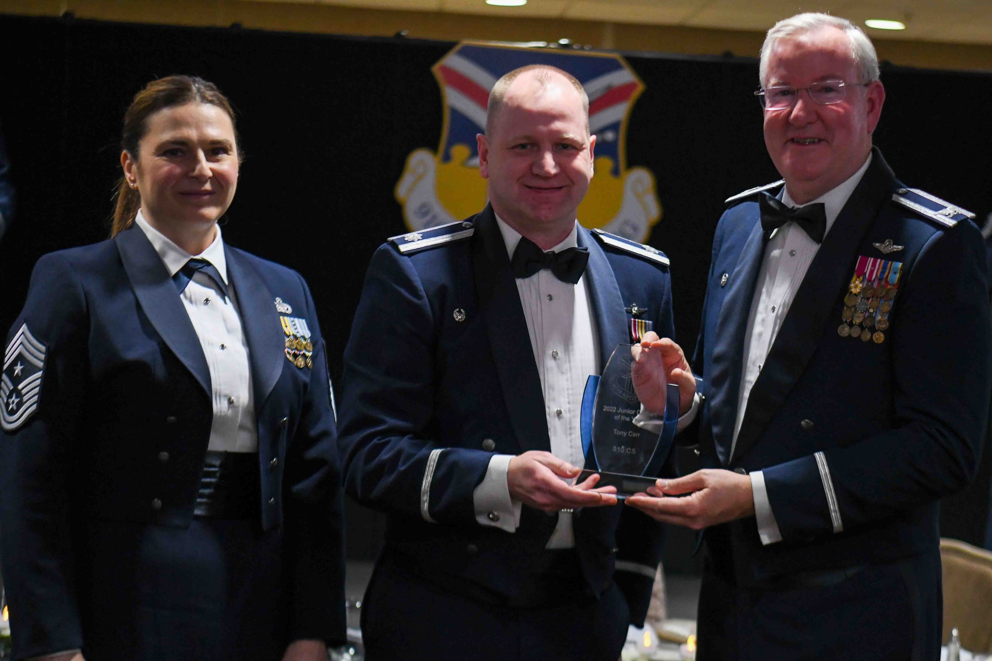 Lt. Col. Marc Meyer, 910th Communications Squadron commander, receives an award on behalf of Tony Carr, a management assistant with the 910th Communications Squadron, from 910th Airlift Wing Commander Col. Jeff Van Dootingh (right) and 910th AW Command Chief Master Sgt. Jennifer McKendree (left), during the unit’s annual awards banquet, March 4, 2023, at Youngstown Air Reserve Station, Ohio.