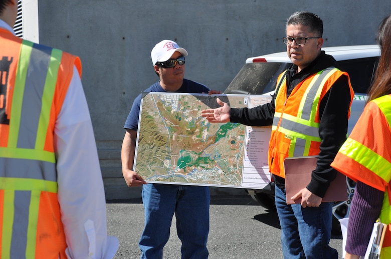 Phil Serpa, right, and Richard Lee, U.S. Army Corps of Engineers Los Angeles District Operations Division, explain the Prado Dam spillway modification project for Travis Tutka, senior Dam and Levee Safety Branch program manager, using an overview photo of the site, March 9, near Corona, California.