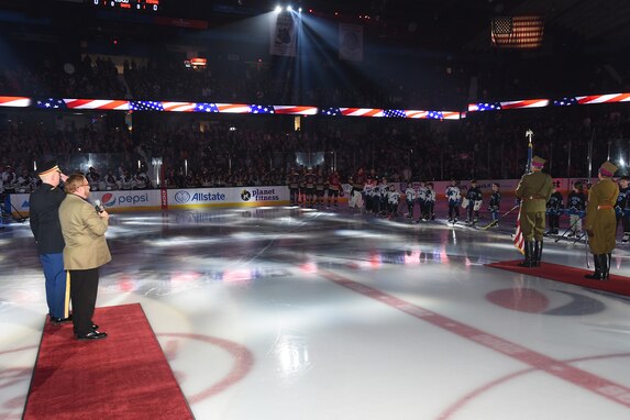 U.S. Army Reserve Lt. Col. Joseph Shalosky, left, renders a salute during the playing of the National Anthem at a Chicago Wolves military recognition game, March 11, 2023.