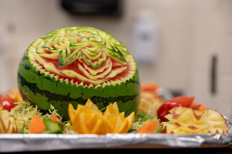 Fruit carving designs are displayed before lunch service during an inspection for the Maj. Gen. William Pendleton Thompson Hill Memorial Awards for Food Service Excellence at the 12th Marines Mess Hall on Camp Hansen, Okinawa, Japan, March 1, 2023. The 12th Marines Mess Hall competed amongst its counterparts for the WPT Hill Memorial award for Marine Corps Mess Hall of the Year. Marine and National Restaurant Association Education Foundation evaluators observed administrative, managerial, and food service operations during lunch preparation, and later gave their remarks to recognize the accomplishments of Marines and Master labor contractors. (U.S. Marine Corps photo by Lance Cpl. Thomas Sheng)