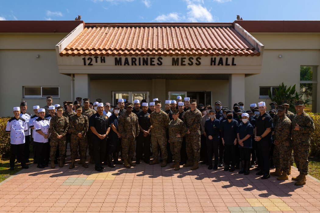 U.S. Marines and master labor contractors pose for a group photo after an inspection for the Maj. Gen. William Pendleton Thompson Hill Memorial Awards for Food Service Excellence at the 12th Marines Mess Hall on Camp Hansen, Okinawa, Japan, March 1, 2023. The 12th Marines Mess Hall competed amongst its counterparts for the WPT Hill Memorial award for Marine Corps Mess Hall of the Year. Marine and National Restaurant Association Education Foundation evaluators observed administrative, managerial, and food service operations during lunch preparation, and later gave their remarks to recognize the accomplishments of Marines and master labor contractors. (U.S. Marine Corps photo by Lance Cpl. Thomas Sheng)