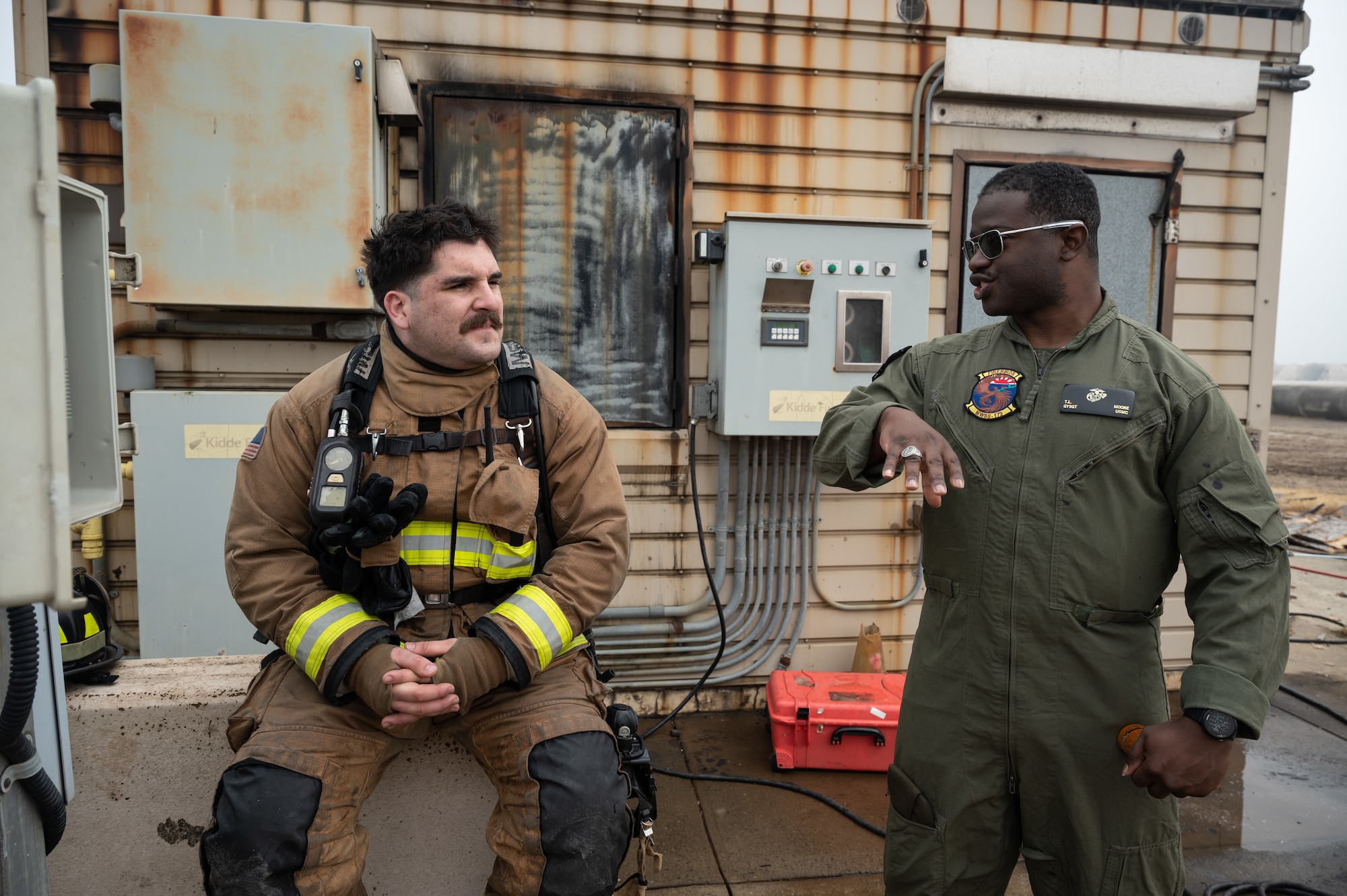 U.S. Air Force Staff Sgt. Bobby Arguelles (left), 8th Civil Engineer Squadron firefighter, speaks with U.S. Marine Corps Gunnery Sgt. T.L. Moore, Marine Wing Support Squadron 172 aircraft rescue firefighter specialist, at Kunsan Air Base, Republic of Korea, Mar. 9, 2023. Several leaders from Camp Foster, Okinawa, Japan, came to spectate the training event to understand the benefits of installing similar training equipment at their location. (U.S. Air Force photo by Staff Sgt. Sadie Colbert)