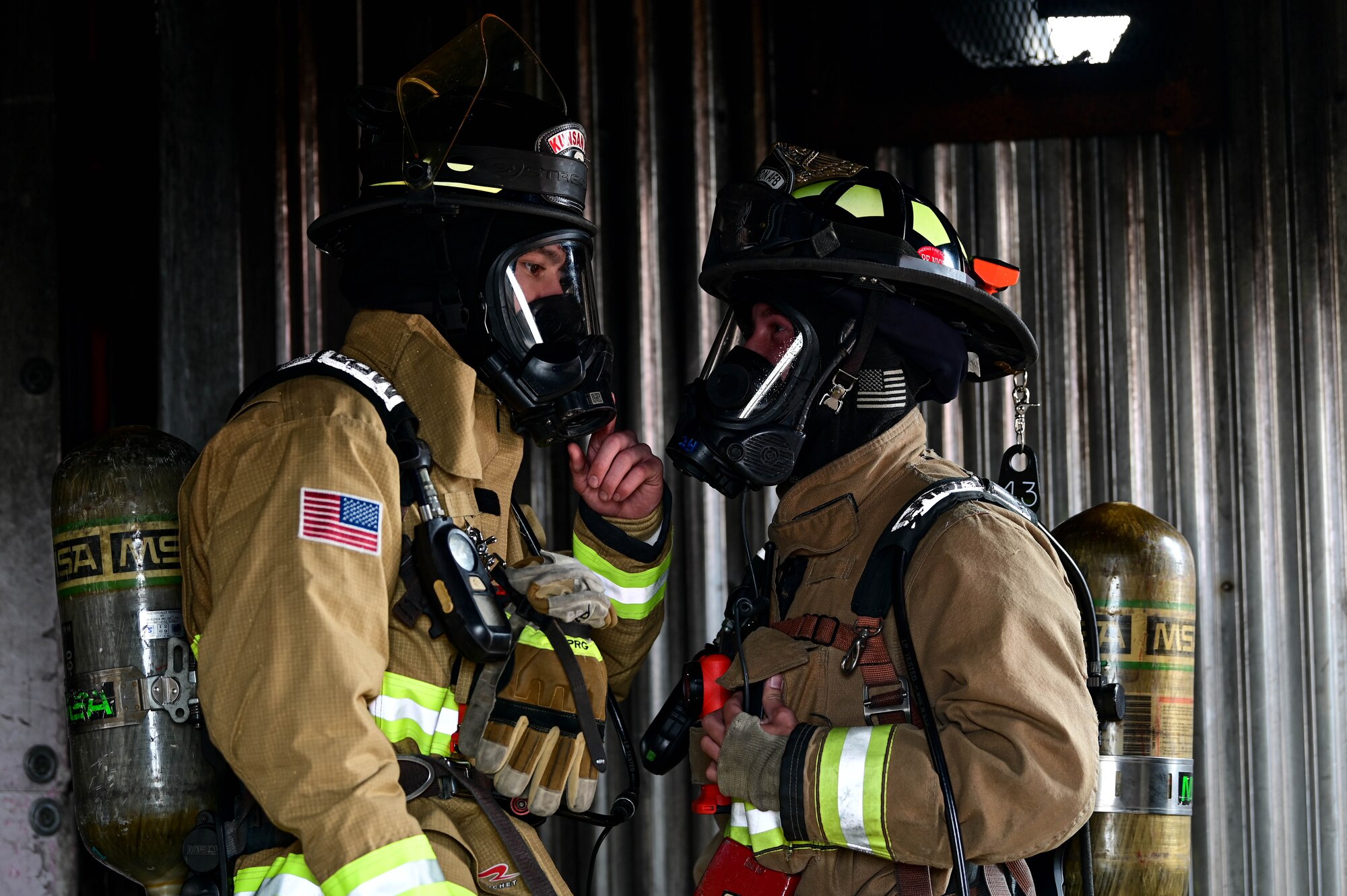 U.S. Air Force Airman 1st Class Dawson Worthy (left), and Staff Sgt. Charles Rogers, 8th Civil Engineer Squadron firefighters, discuss a scenario inside a burn house during a joint training event at Kunsan Air Base, Republic of Korea, Mar. 9, 2023. Firefighter personal protective equipment is designed to protect firefighters from injuries or illnesses resulting from contact with fire and other hazards. (U.S. Air Force photo by Senior Airman Shannon Braaten)
