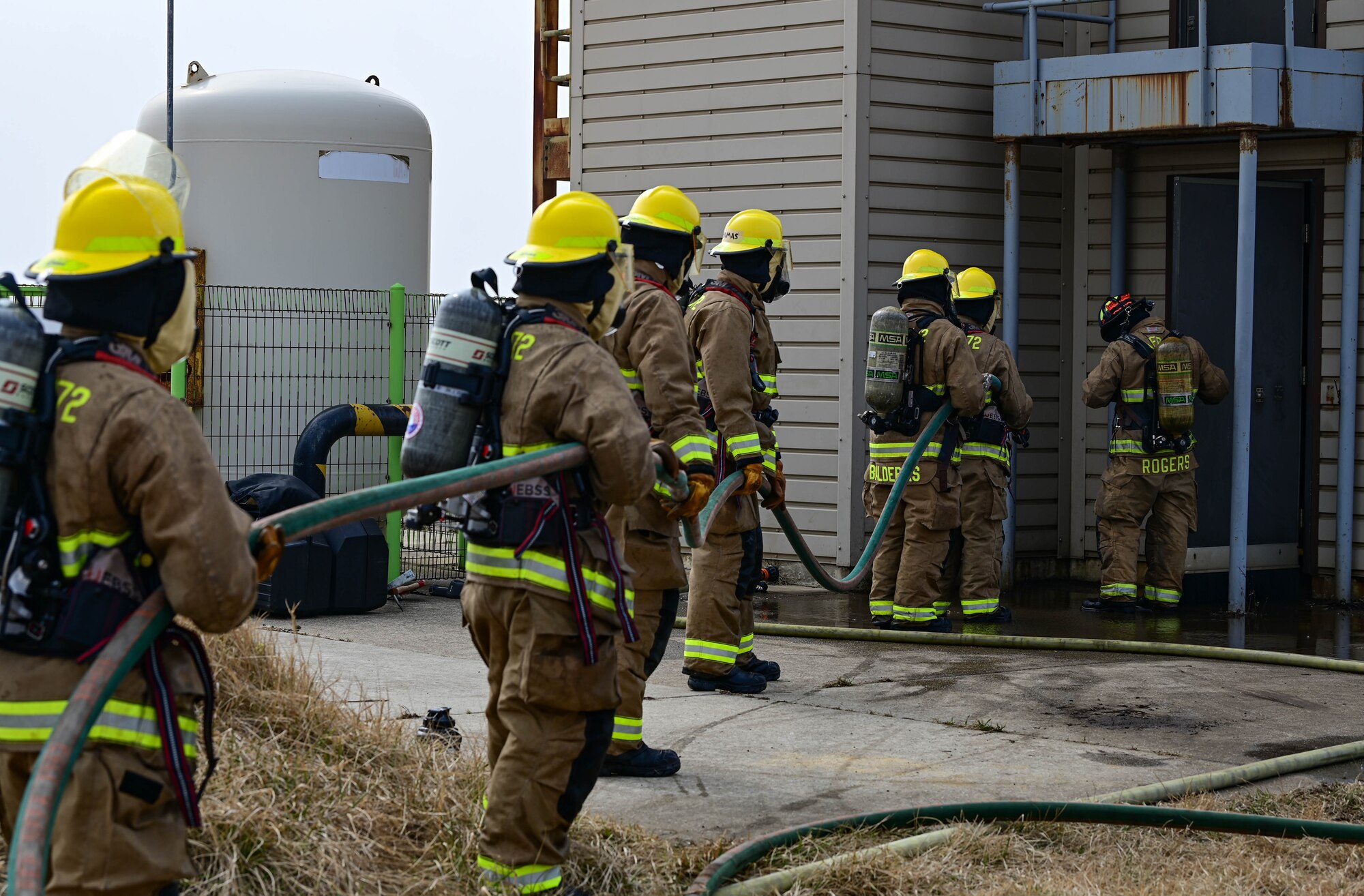 Firefighters from the U.S. Air Force 8th Civil Engineer Squadron and U.S. Marine Corps Marine Wing Support Squadron 172, Camp Foster, Okinawa, Japan, prepare to enter a burn house during a joint training event at Kunsan Air Base, Republic of Korea, Mar. 9, 2023. Both teams battled real, controlled flames while sharing techniques and sharpening their capabilities as first responders. (U.S. Air Force photo by Senior Airman Shannon Braaten)