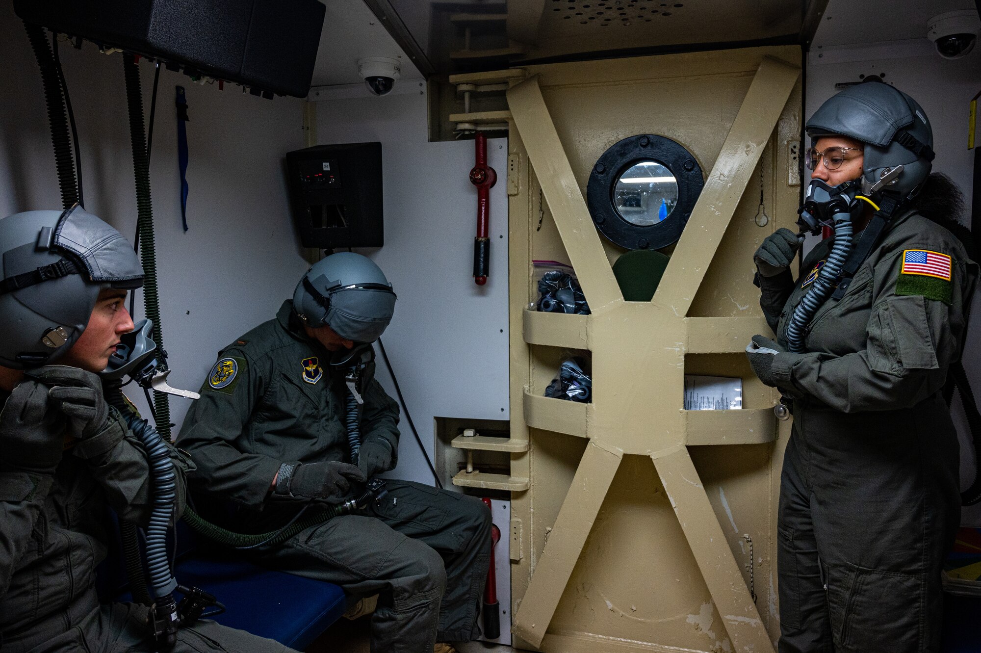 U.S. Air Force Senior Airman Jada Peters instructs students how to correctly use aircraft equipment in the altitude chamber at Laughlin Air Force Base, Texas, on Feb. 24, 2023. The altitude chamber is one of the first training steps for all new pilots and aircrew to demonstrate and know the symptoms of hypoxia. (U.S. Air Force photo by Senior Airman David Phaff)