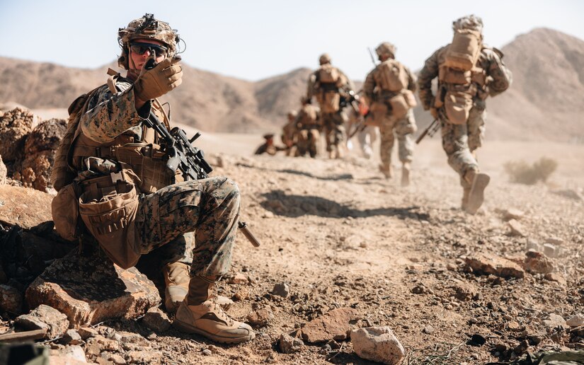 Marines move through a desert terrain.